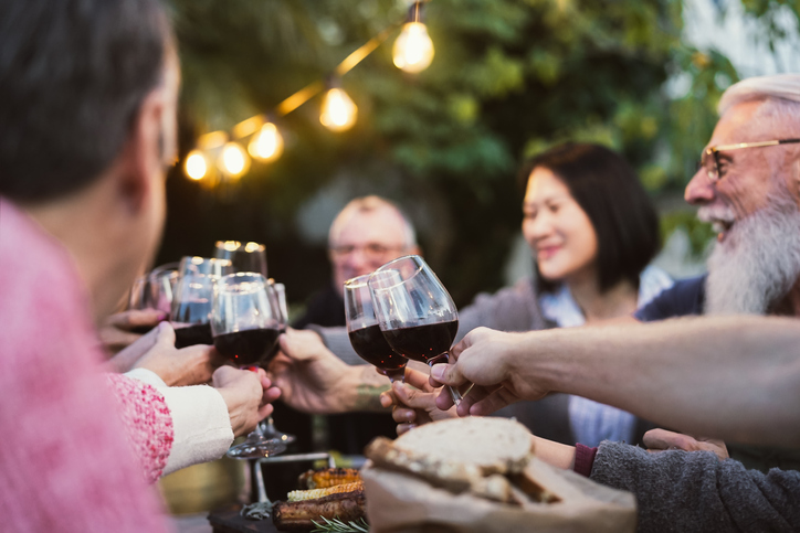 Happy family dining and tasting red wine glasses in barbecue dinner party – People with different ages and ethnicity having fun together